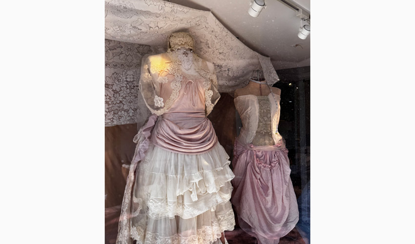 photo of window display featuring white and pink lace and silk dresses