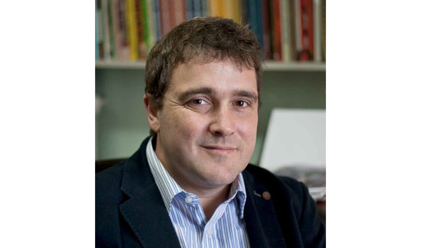 portrait of a man in a suit looking into the camera against an office backdrop