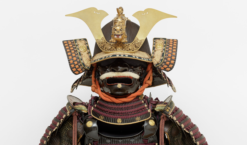photo detail of a Japanese suit of armor helmet against an off white backdrop