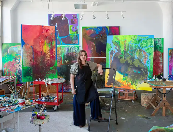 Artist Vian sora standing in front of several of her paintings