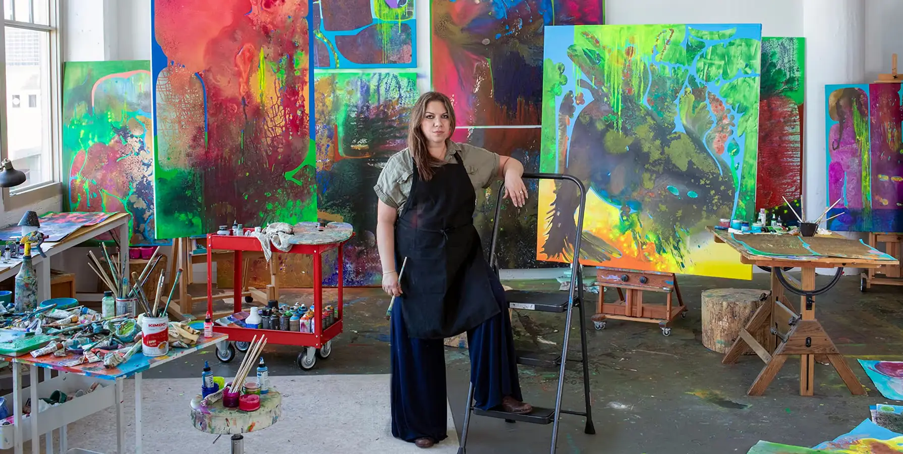 Artist Vian sora standing in front of several of her paintings