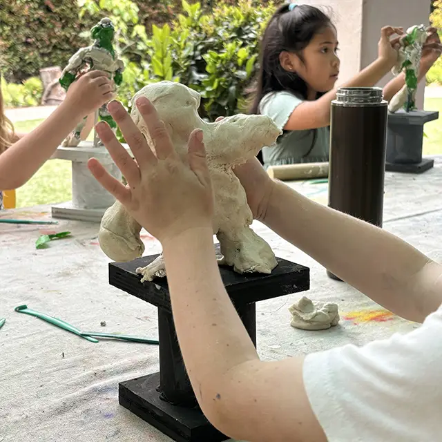 photo of child pushing clay on table platform