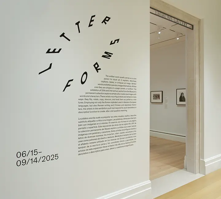 photo of a white wall with text next to an entrance to a gallery