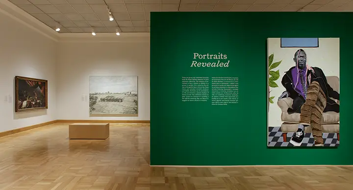 photo of two gallery walls with paintings of portraits on them