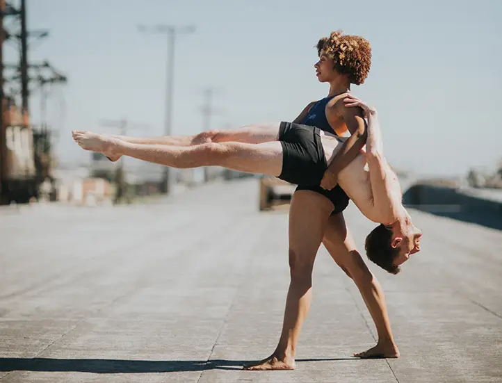 photo of a couple performing modern dance including an upright woman supporting a horizontal man