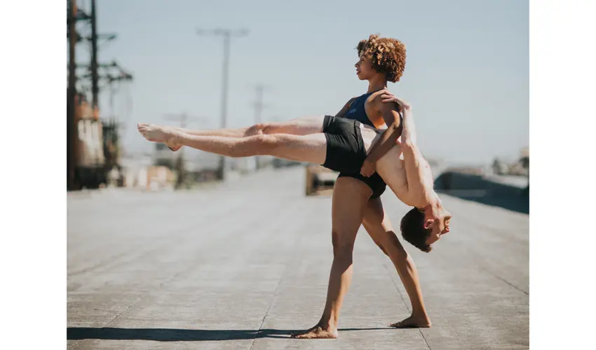 photo of a couple performing modern dance including an upright woman supporting a horizontal man