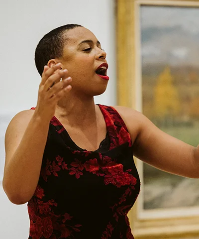 photo of opera singer in red dress singing in museum gallery