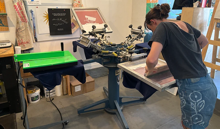 photo of someone using a screen printing machine