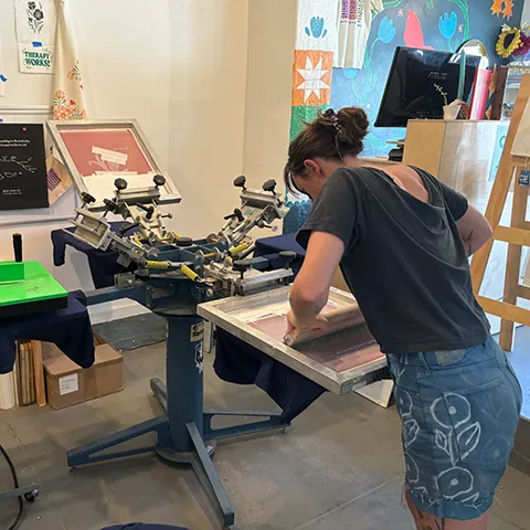 photo of someone using a screen printing machine