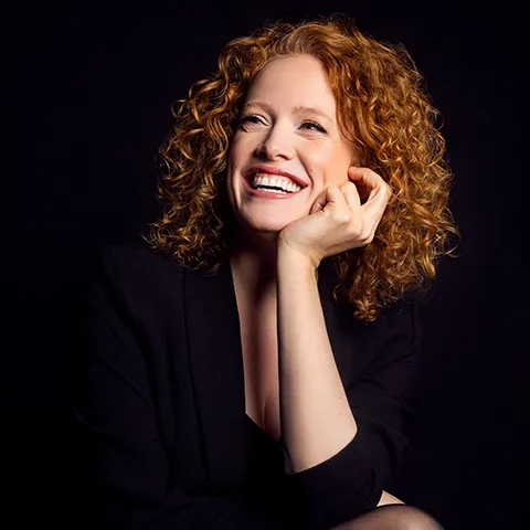 photo of a redheaded person looking away from the camera against a dark background