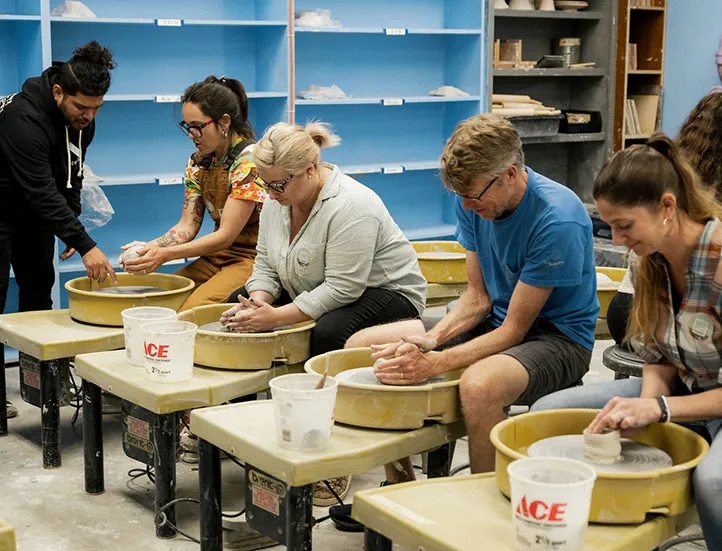 photo of adult students working with handbuilding clay led by instructor