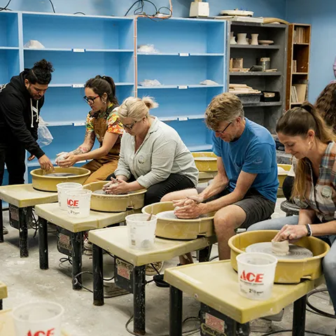 photo of adult students working with handbuilding clay led by instructor