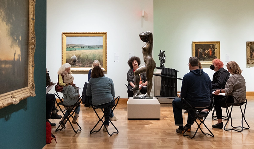 photo of people in a gallery sketching a sculpture