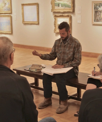 photo of people in a gallery around a person on a bench instructing