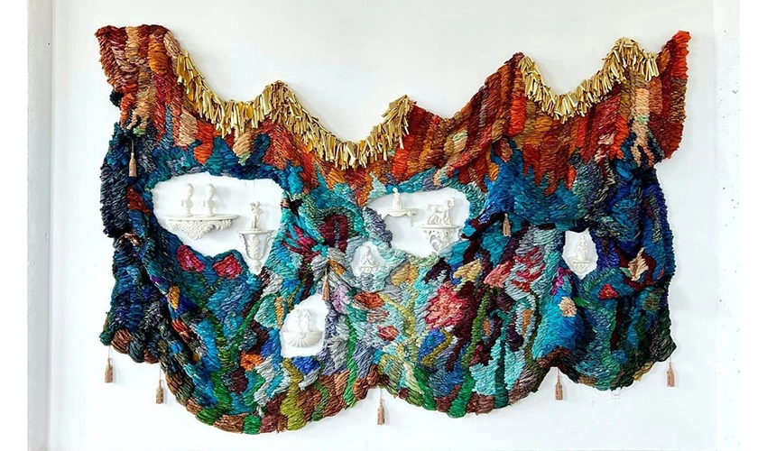 photo of colorful wall hanging surrounding sculptural objects