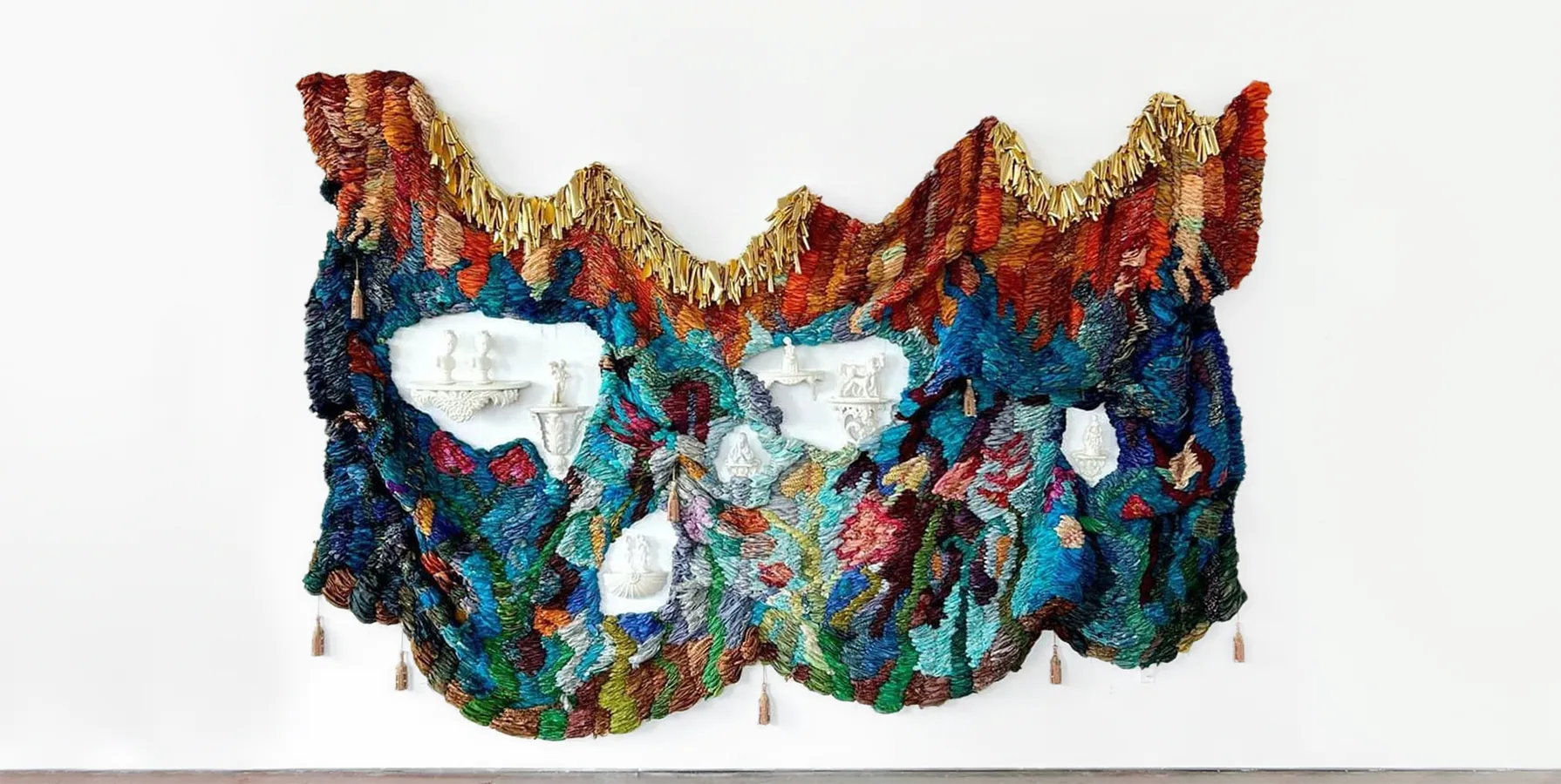 photo of colorful wall hanging surrounding sculptural objects