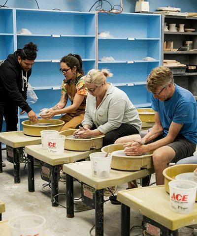 photo of adult students working with handbuilding clay led by instructor