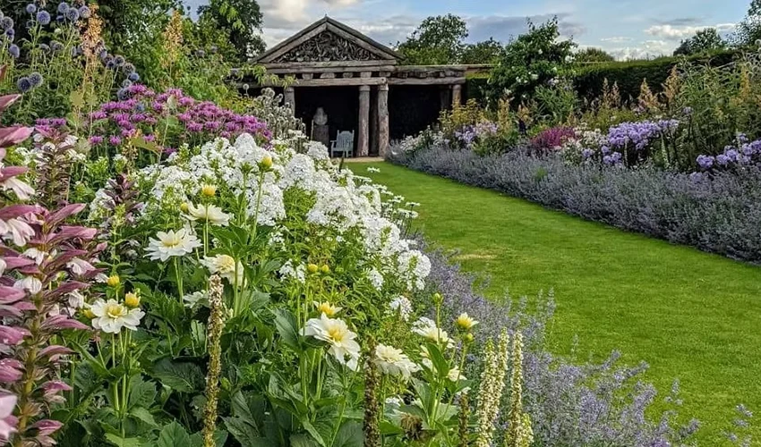 Photo of garden with flowers in foreground and ancient looking structure in the background