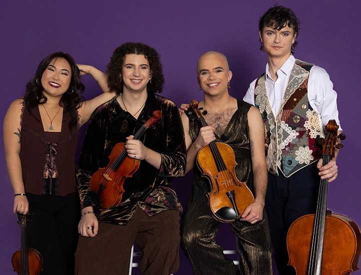 photo of four young musicians seated and standing and holding their string instruments against a purple backdrop