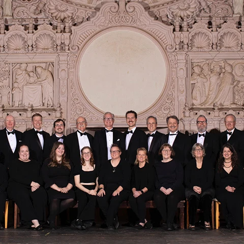 group of musicians in tuxedos seated and standing in a row for the camera