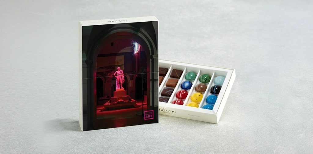 photo of box of colorful chocolates and its box featuring a photo of a roman statue bathed in pink light