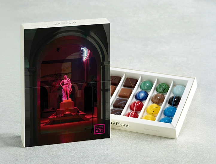 photo of box of colorful chocolates and its box featuring a photo of a roman statue bathed in pink light