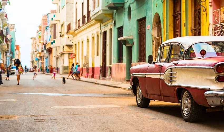 street scene of Havana during the day with children playing in the background and a classic car in the foreground