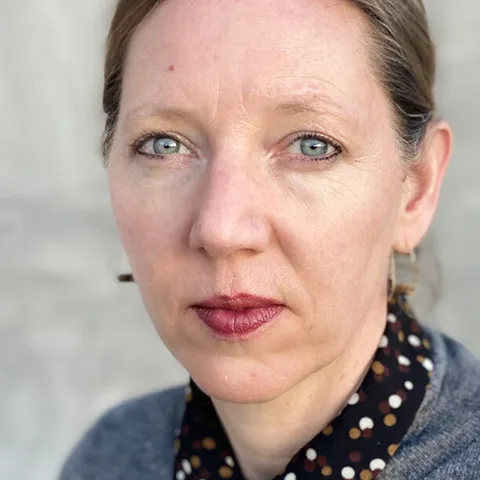 photo of woman with red lipstick and a grey sweater looking into lens