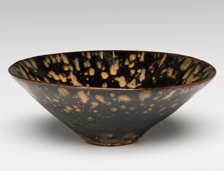 head on and slightly above photo of tortoise shell tea bowl on light gray background