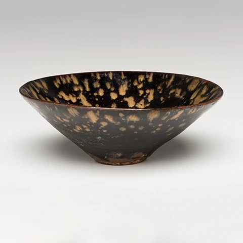 head on and slightly above photo of tortoise shell tea bowl on light gray background