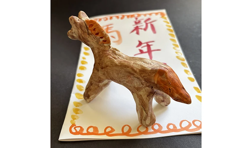 photo of a small clay horse on a white decorated piece of paper