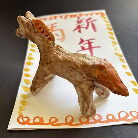 photo of a small clay horse on a white decorated piece of paper