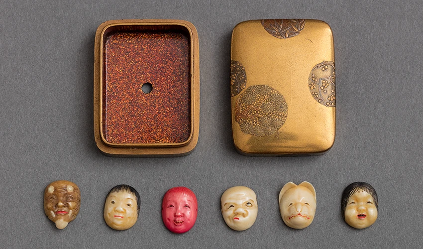 photo of six figural netsukes with open case lying flat on gray table 