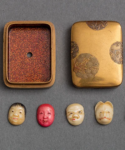 photo of four figural netsukes with open case lying flat on gray table 