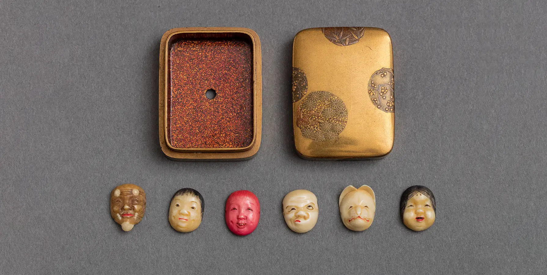 photo of six figural netsukes with open case lying flat on gray table 