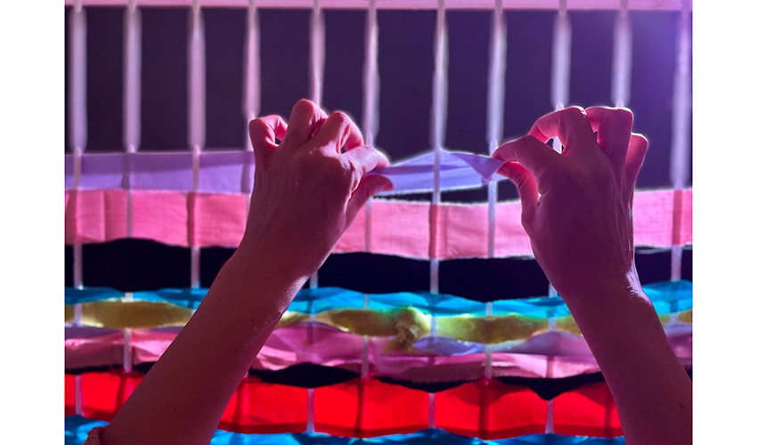 photo of hands working with colorful material in a weave