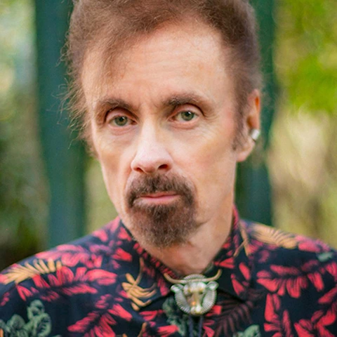 portrait of a goateed man in a colorful shirt with bolo tie