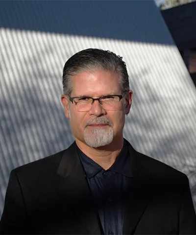 a portrait of the author roberto tejada in glasses and a dark suit