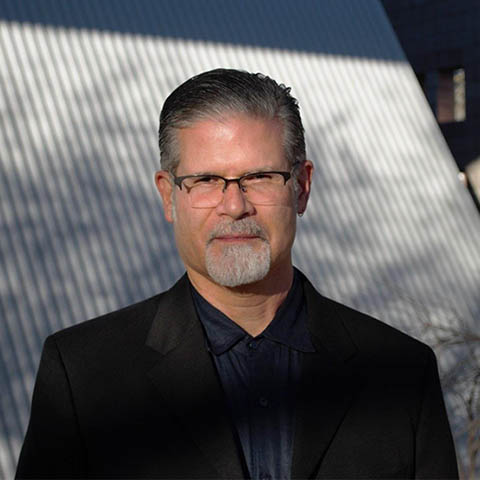 a portrait of the author roberto tejada in glasses and a dark suit