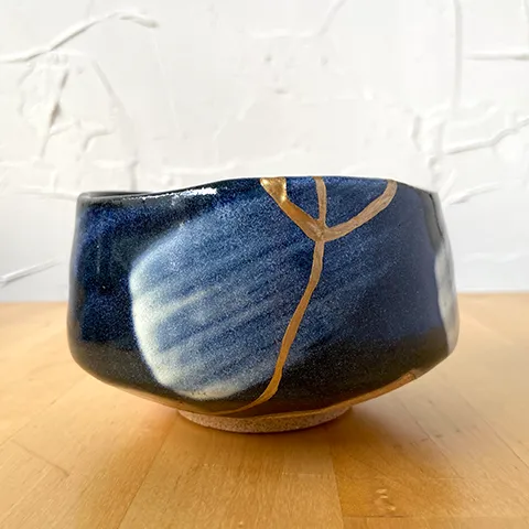 blue ceramic bowl showing a crack in it repaired with gold