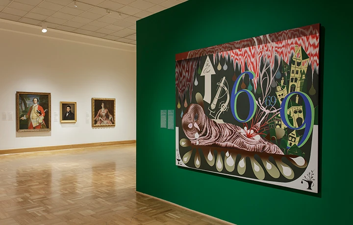 photo of two gallery walls with paintings of portraits spread across them