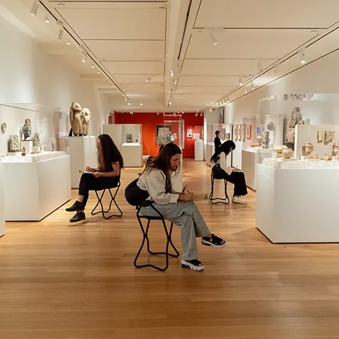 group of seated students drawing in a gallery of Asian art