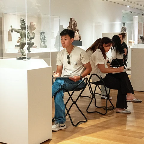 group of seated students drawing in a gallery of Asian art