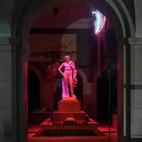 photo of statue of Hermes bathed in pink light in museum gallery
