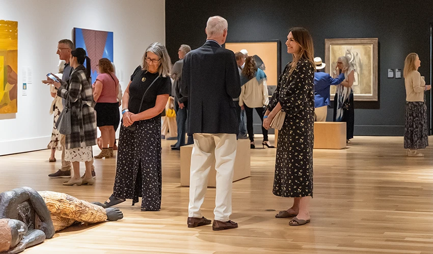 People standing in Museum galleries, talking and looking at art.