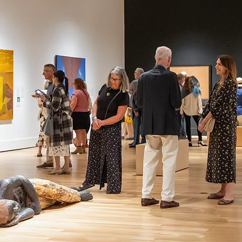 People standing in Museum galleries, talking and looking at art.