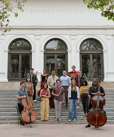 group of young people with their instruments standing on the front steps of the museum entrance
