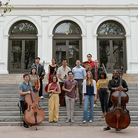 group of young people with their instruments standing on the front steps of the museum entrance
