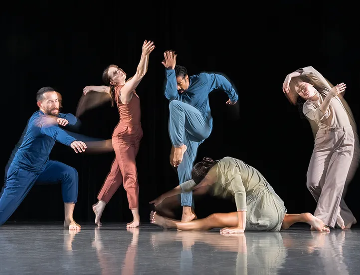 photo of dancers posing in jumpsuits against a dark backdrop