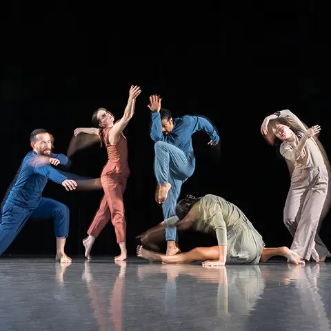 photo of dancers posing in jumpsuits against a dark backdrop